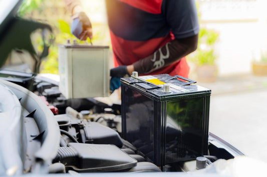 A  battery technician putting in new car battery